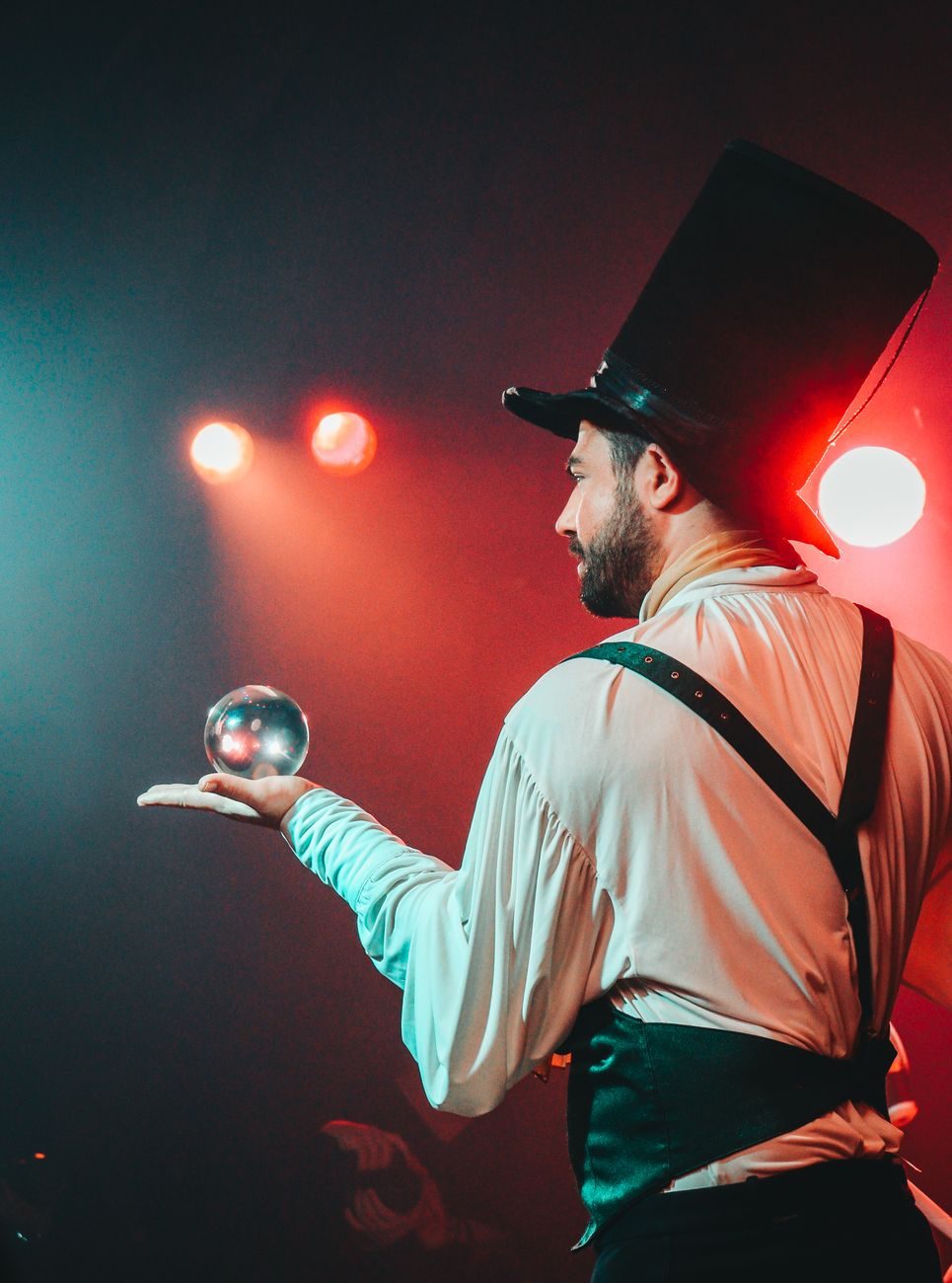 Mago ilusionista en el escenario con bola de cristal y luces de teatro para show