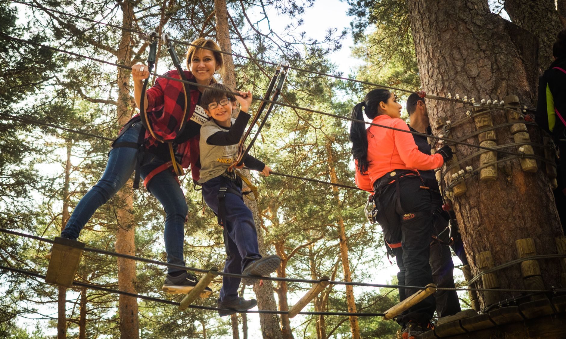 Adulto y niño superando un puente de cuerdas en los árboles del parque Aventura Amazonia Marbella.