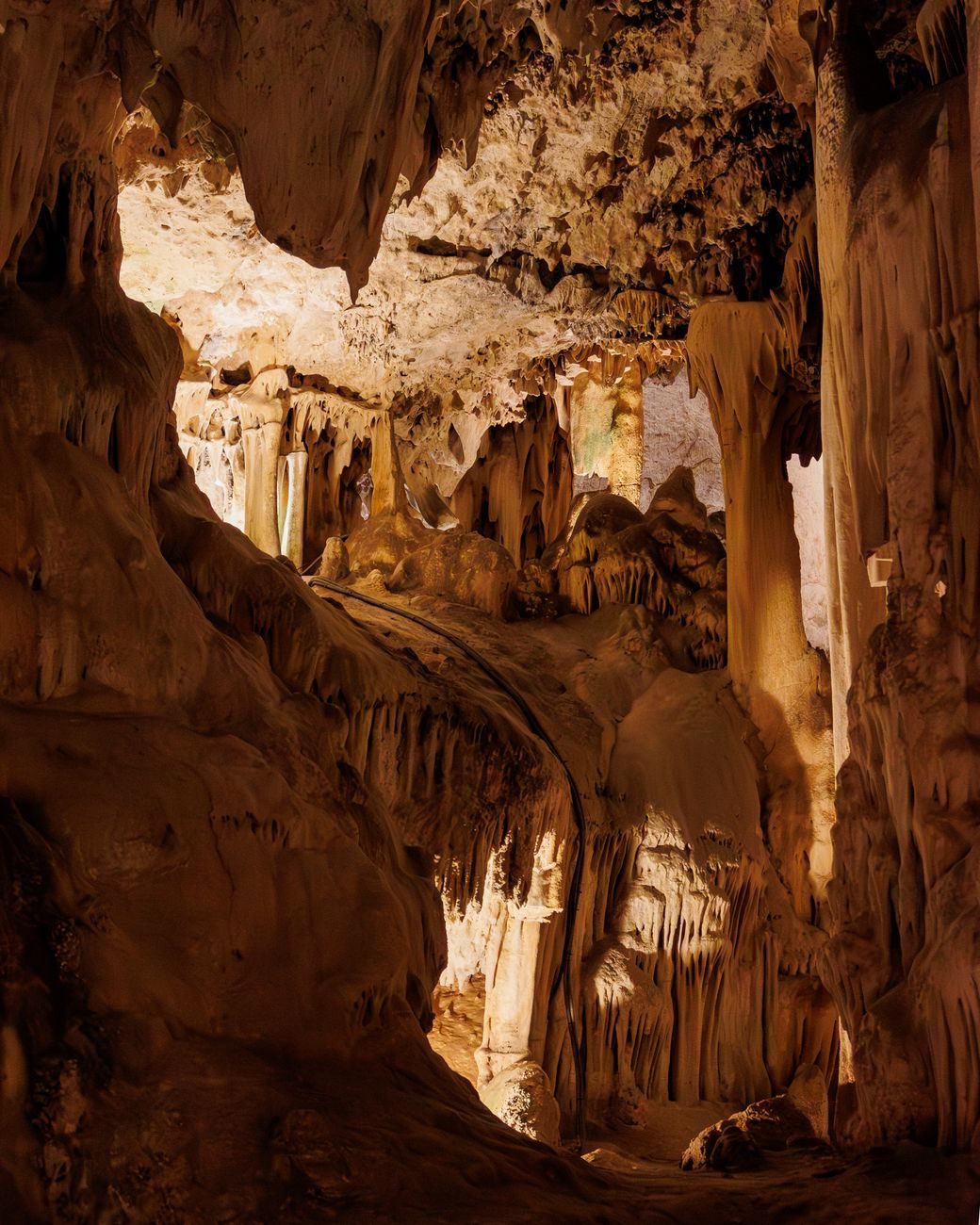 A magnificent formation of stalactites and calcareous columns illuminated with warm tones inside the Nerja Cave