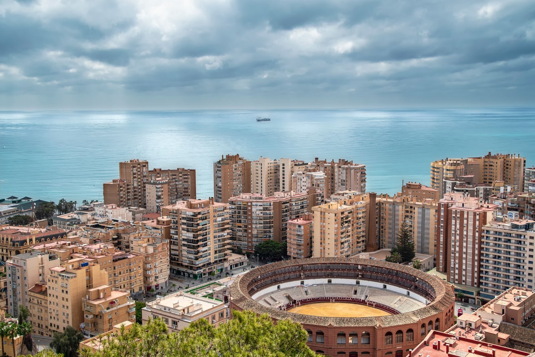 Vista panorámica de la plaza de toros de La Malagueta en Málaga, rodeada de edificios y con el mar Mediterráneo al fondo