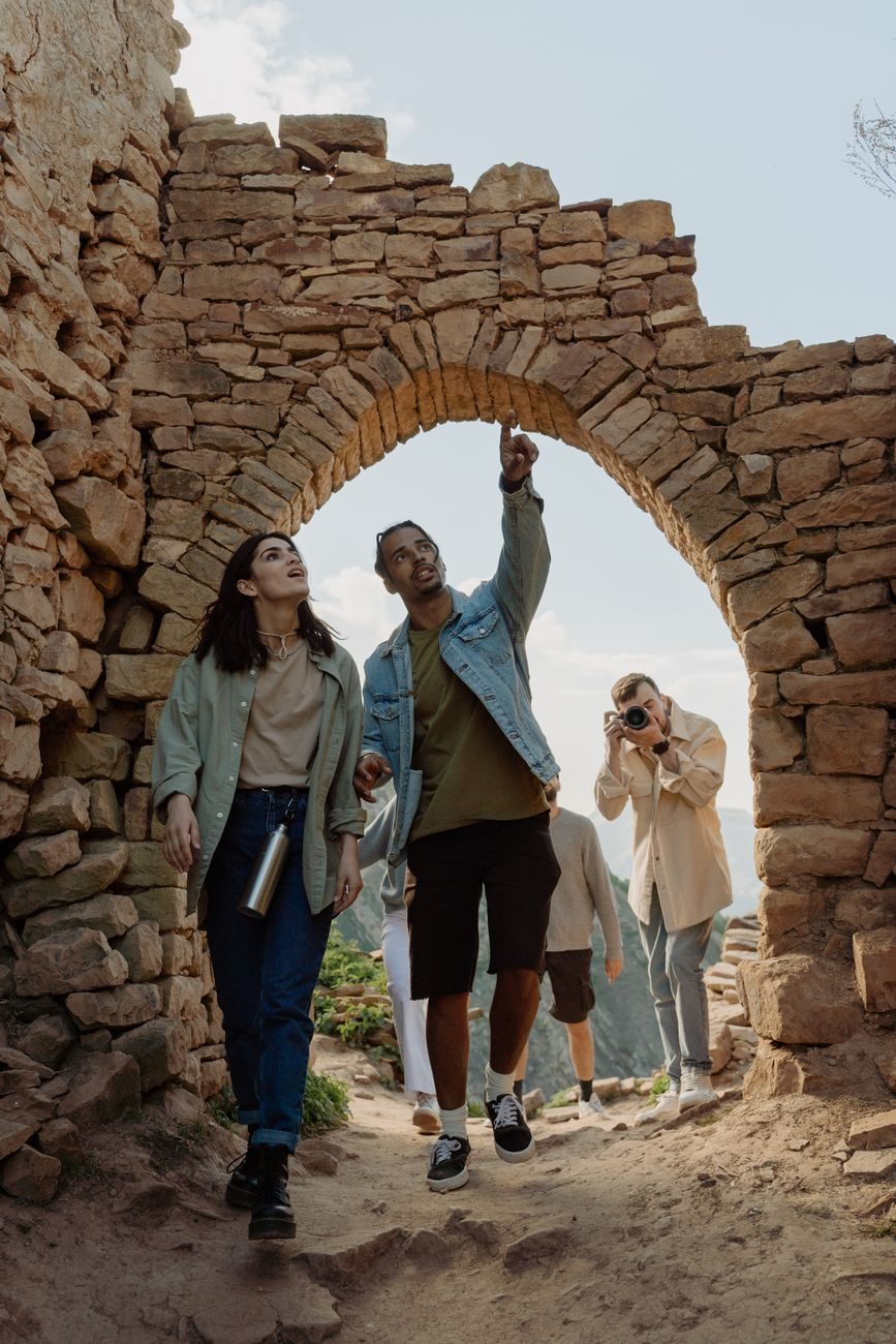 Grupo de turistas realizando una excursión guiada por unas ruinas arqueológicas de piedra al aire libre