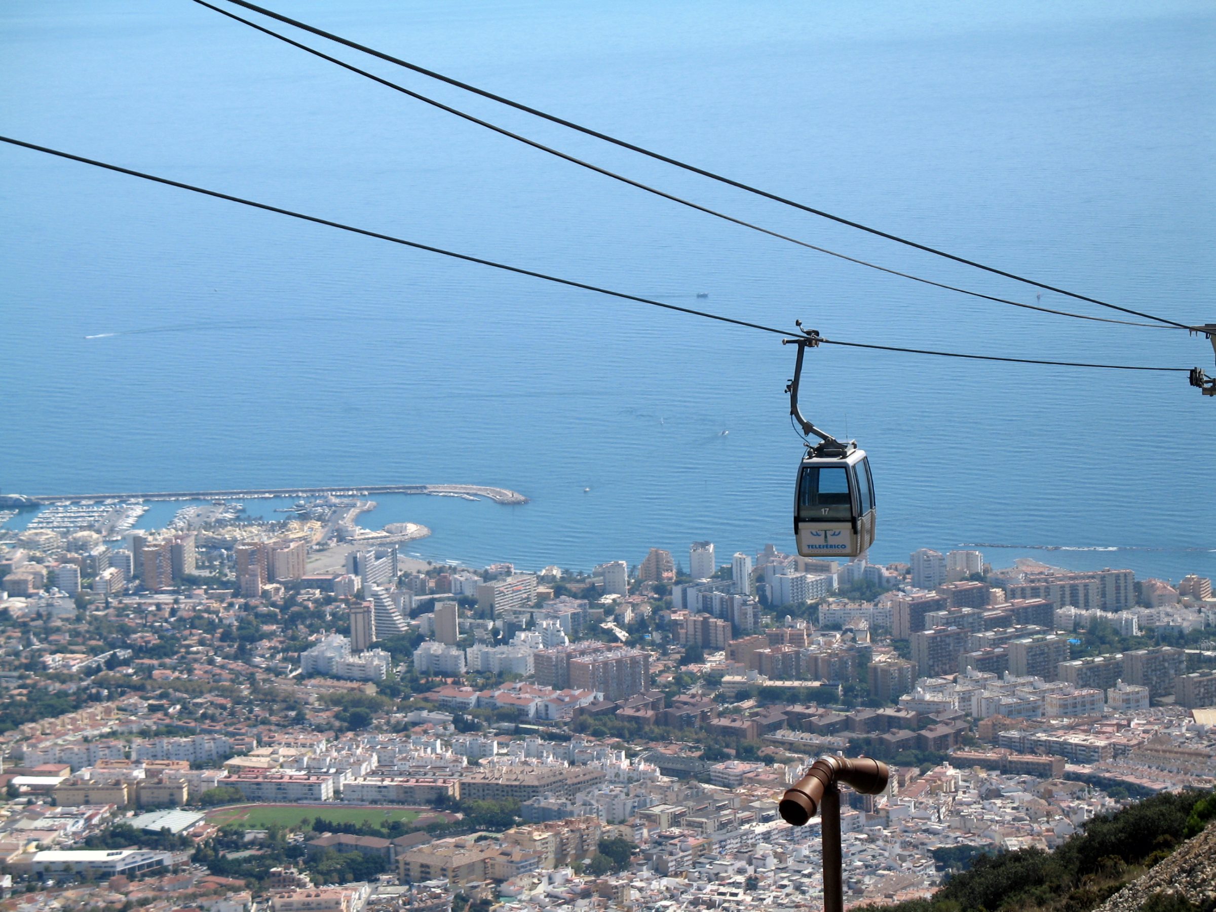 Cabinas del Teleférico de Benalmádena sobre la ladera del monte, con la ciudad y el mar Mediterráneo al fondo.