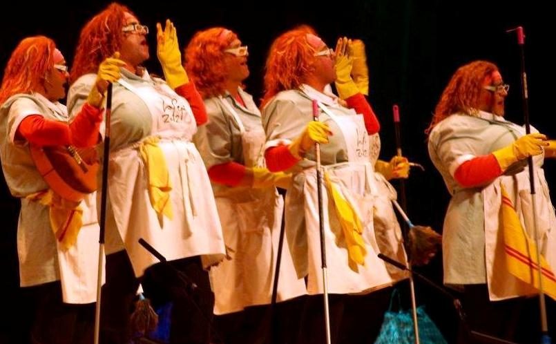 Esta imagen muestra una chirigota o comparsa actuando sobre un escenario en un teatro.