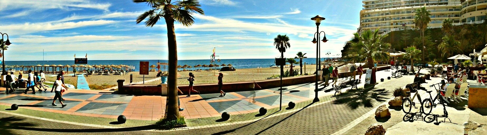 Paseo marítimo de la playa del Bajondillo en Torremolinos con palmeras, vistas al mar Mediterráneo y zona de chiringuitos en la Costa del Sol.